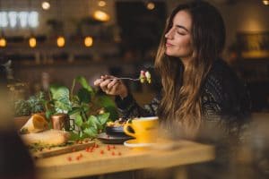 arredamenti per ristoranti, donna soddisfatta mentre mangia, articolo blog COMINshop